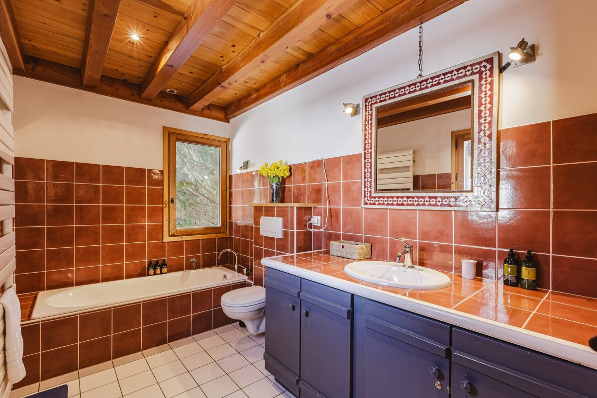 A bathroom with red tiles and a large mirror