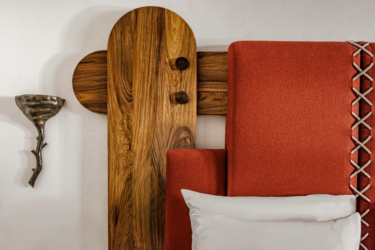 A bed with a wooden headboard and a red blanket