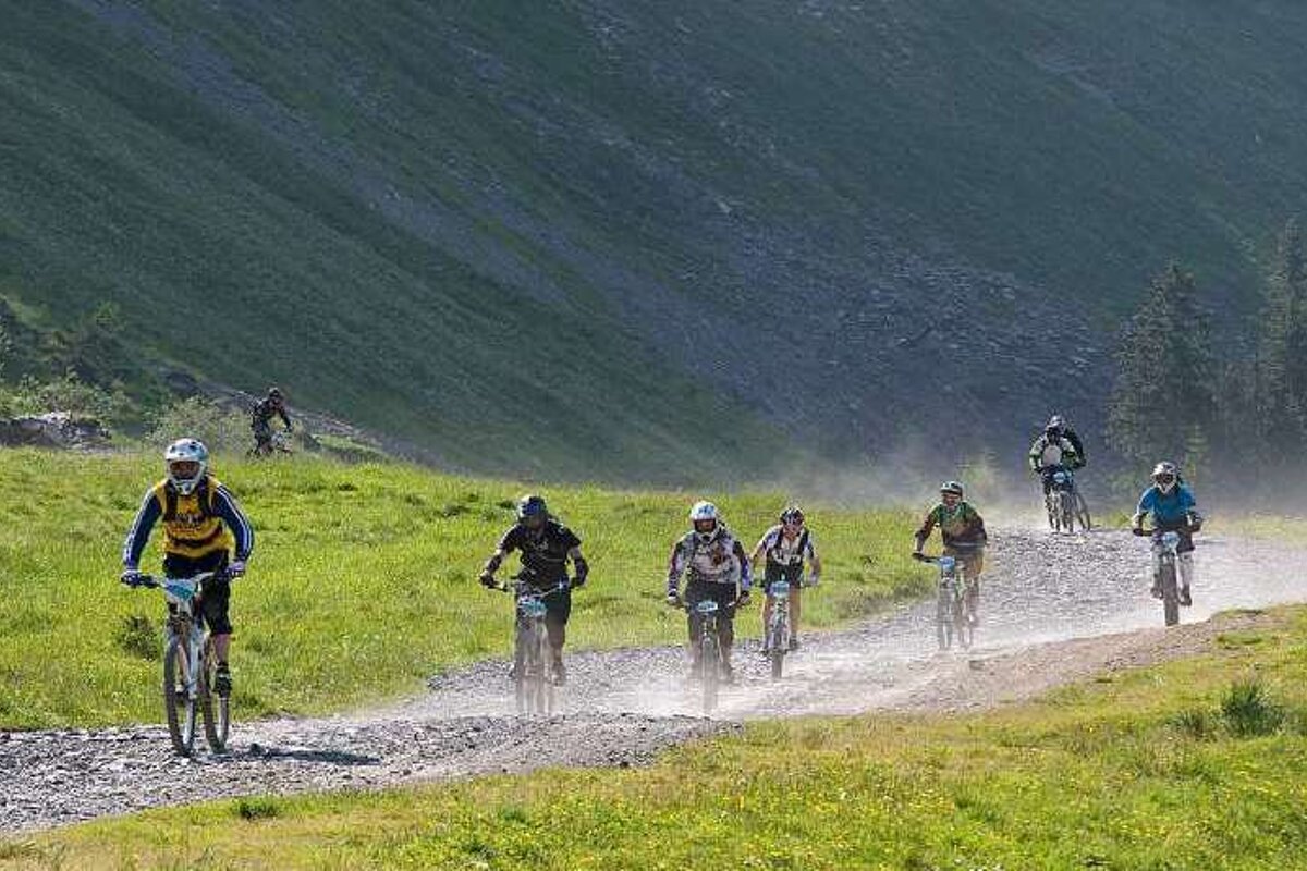 A group of people are riding bicycles down a dirt road