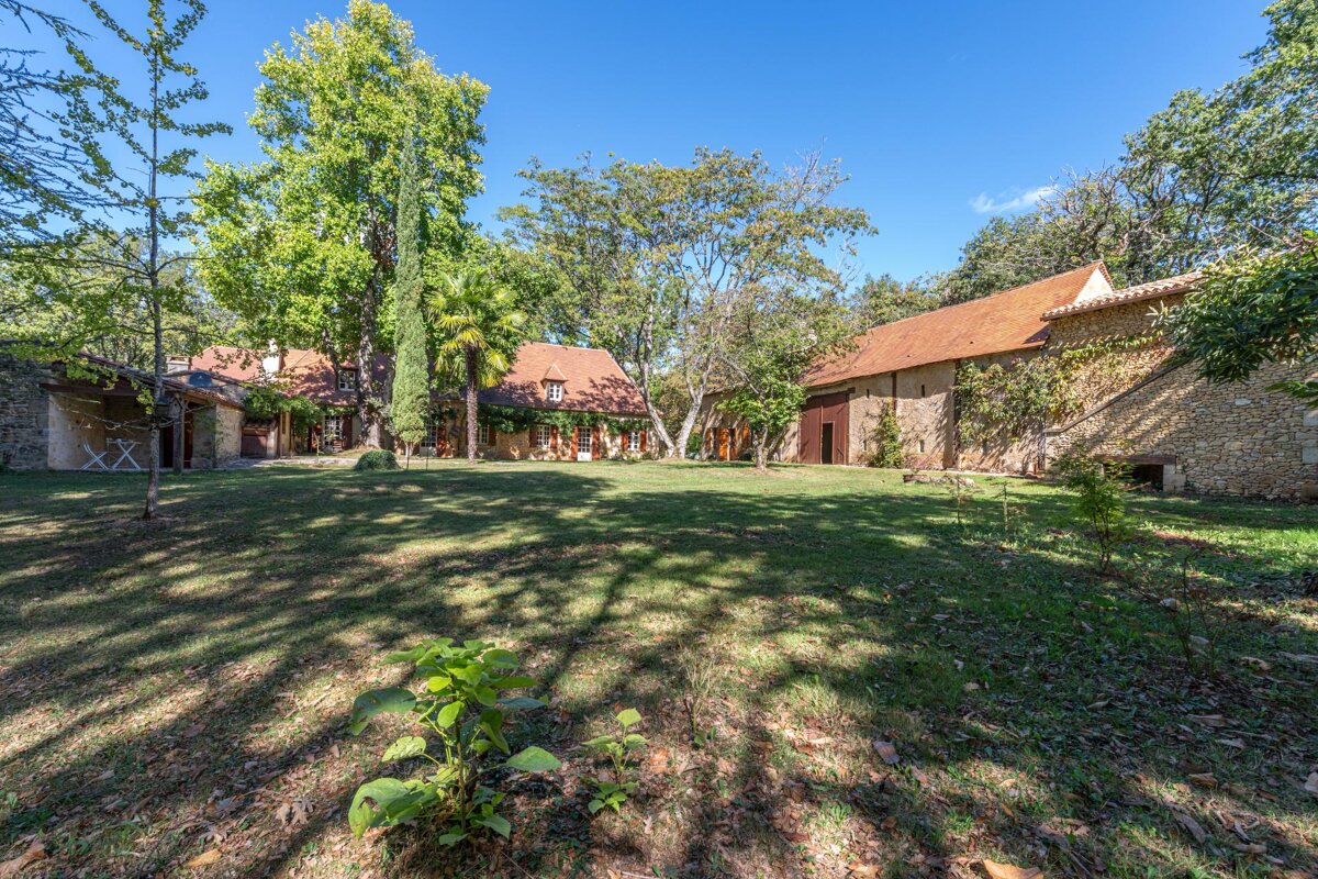 A house with a red roof is surrounded by trees and grass