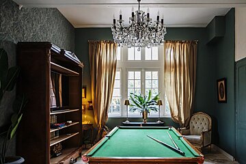 A pool table in a room with a chandelier above it