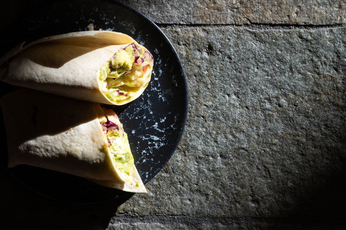 Two wraps on a black plate on a stone surface