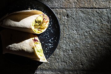 Two wraps on a black plate on a stone surface