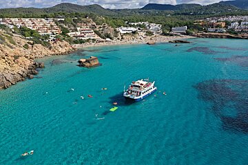 A boat is floating in the water near a beach
