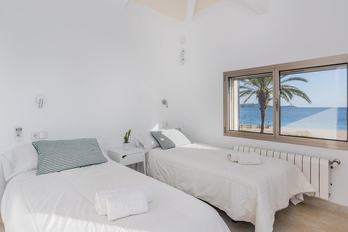 A bedroom with two beds and a window overlooking the ocean