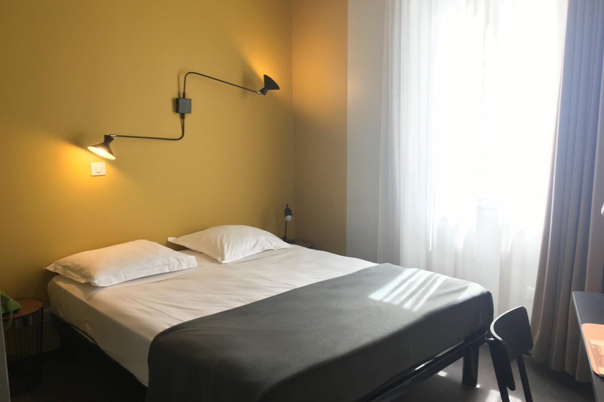 A bedroom with a bed and two lights on the wall
