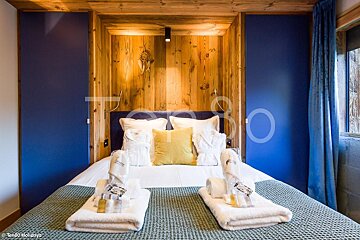 A bedroom with blue walls and a bed with towels on it