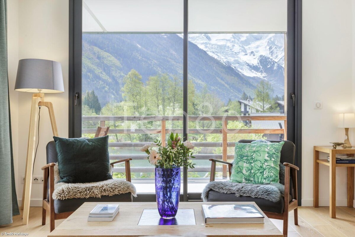 A living room with two chairs and a table with a vase of flowers on it