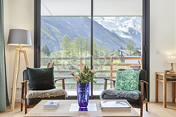 A living room with two chairs and a table with a vase of flowers on it
