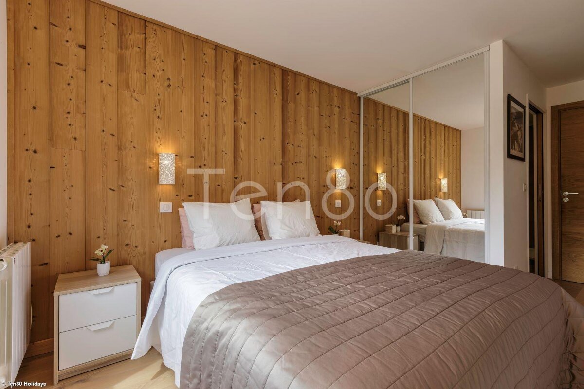 A bedroom with wood paneling and a bed with a blanket on it