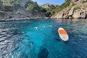 People are swimming in the ocean near a paddle board