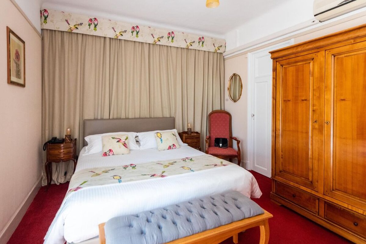 A bedroom with a bed a chair and a wardrobe