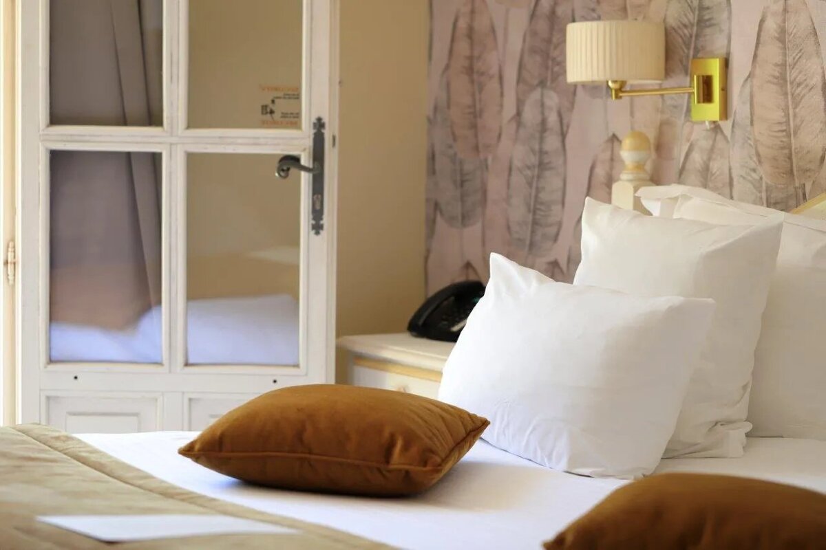 A bed with white sheets and brown pillows in a hotel room