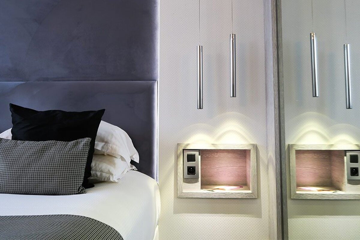 A bed with black pillows and a mirror behind it