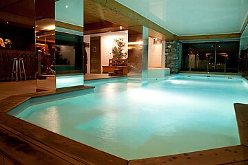 A large indoor swimming pool is lit up at night