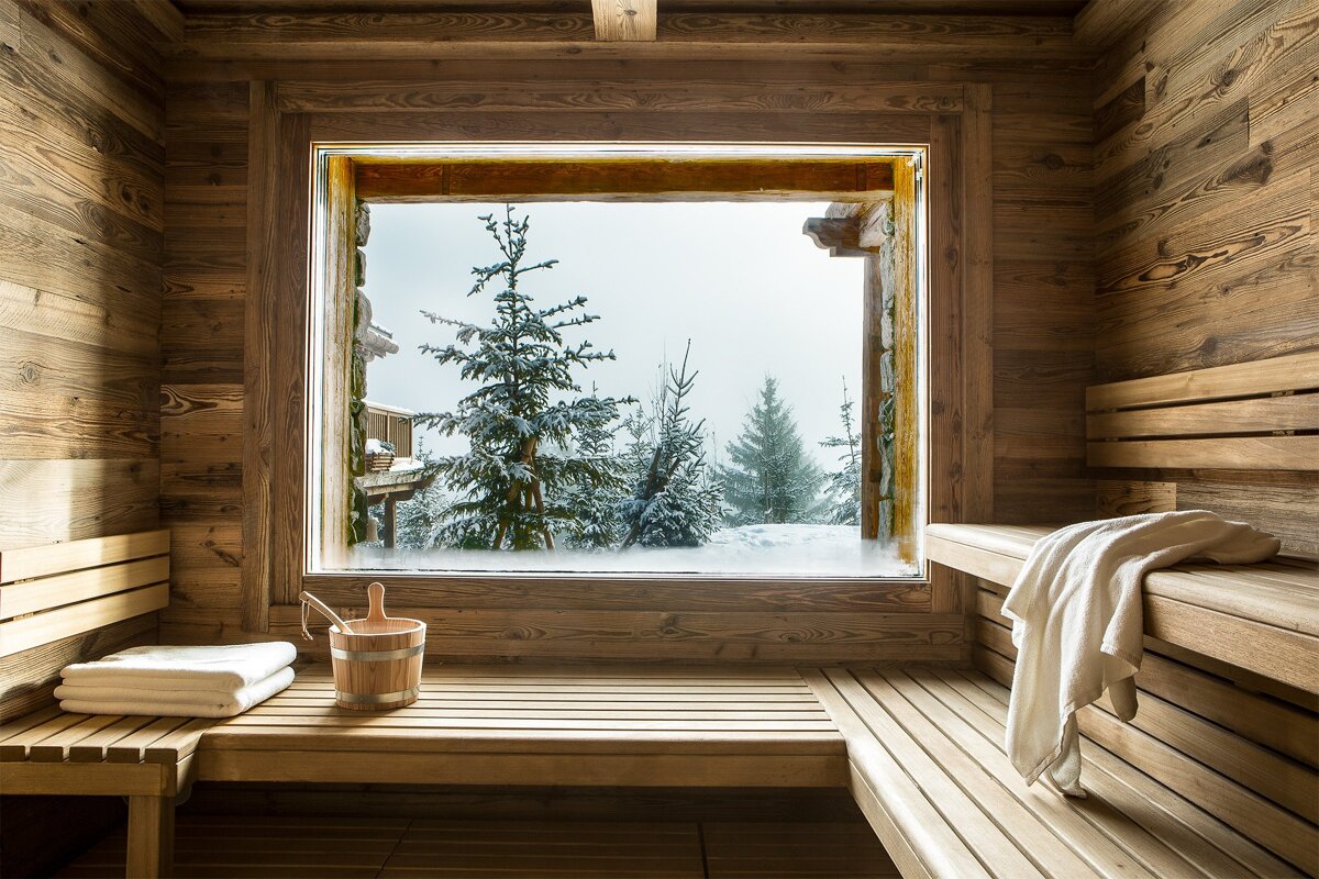 A wooden sauna with a window overlooking a snowy forest
