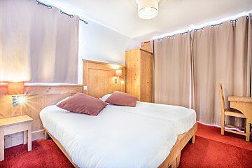 A hotel room with a bed and a desk