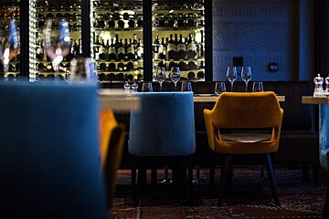 A restaurant with a display of wine bottles in the background