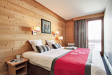 A bedroom with wood paneling and a large bed