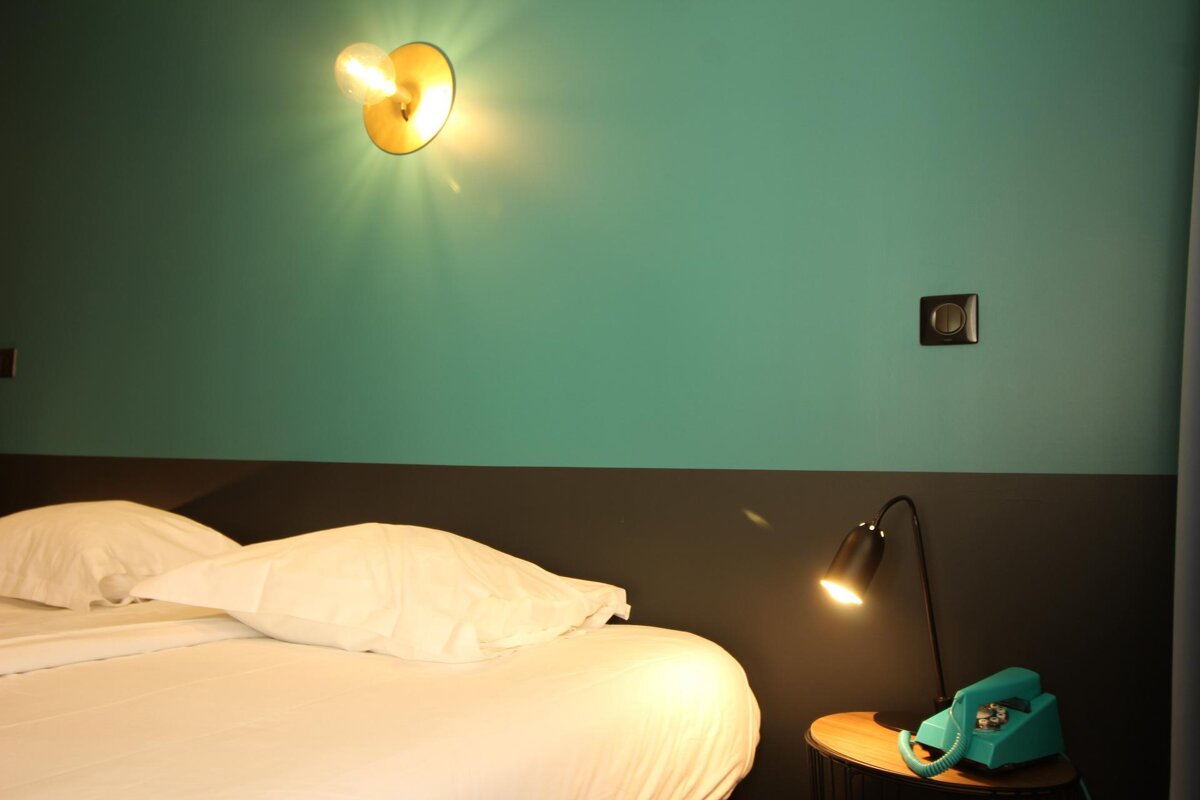 A bed with a lamp and a phone on a nightstand