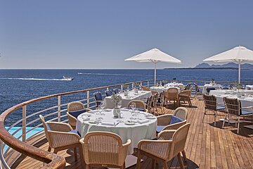 Tables and chairs on a deck overlooking the ocean