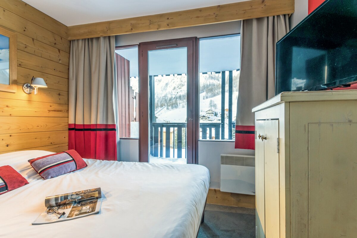 A hotel room with a bed and a television