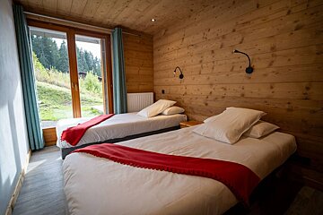 A bedroom with two beds and a large window