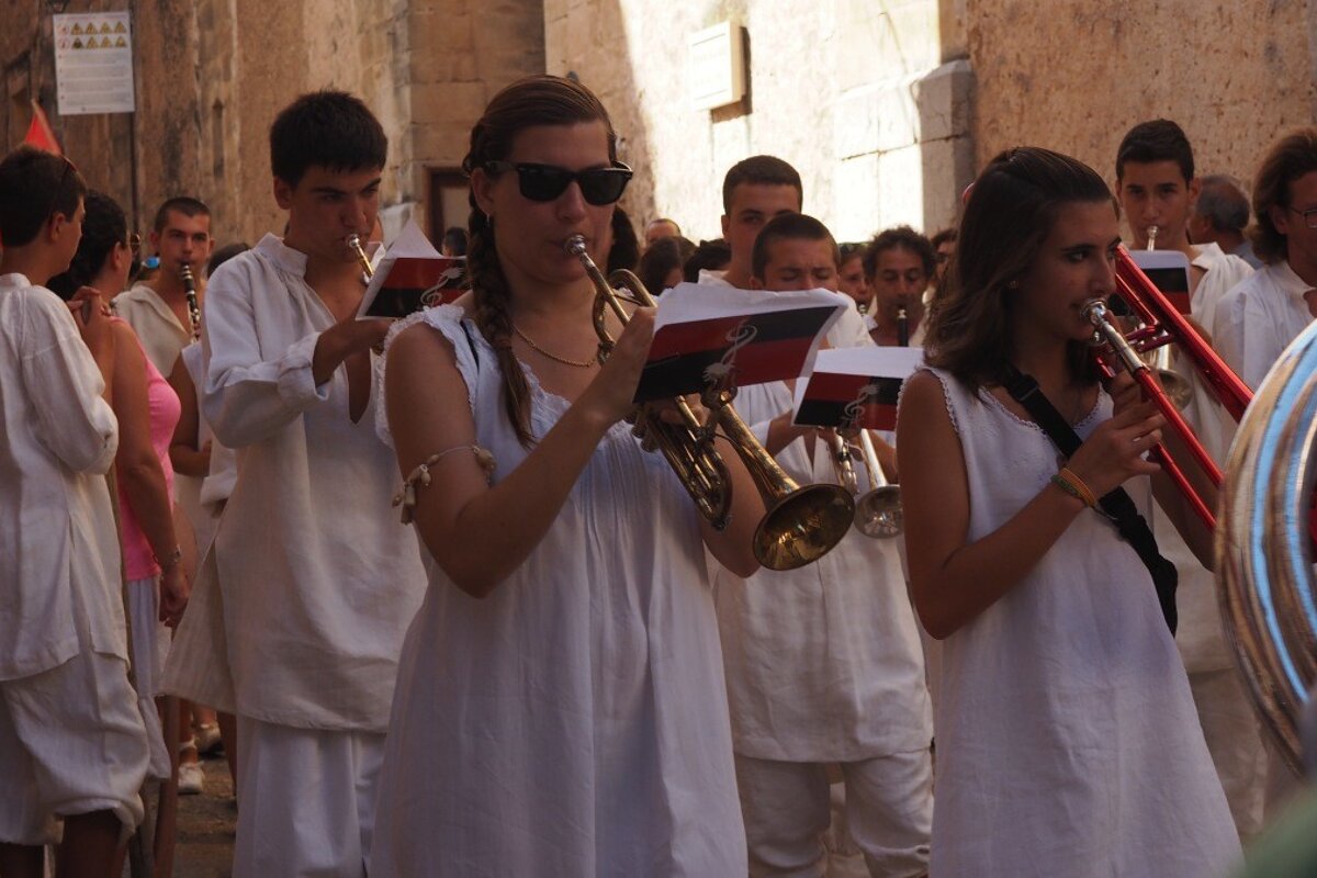 a band dressed in white walking through the streets