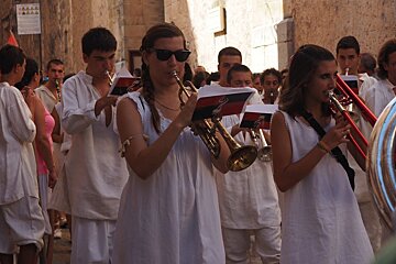 a band dressed in white walking through the streets