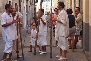 men holding sticks in the street dressed in white