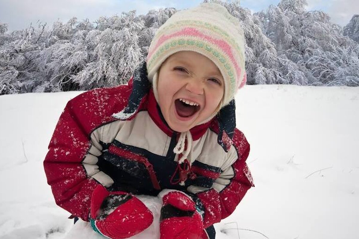 A little girl is playing in the snow with her mouth open