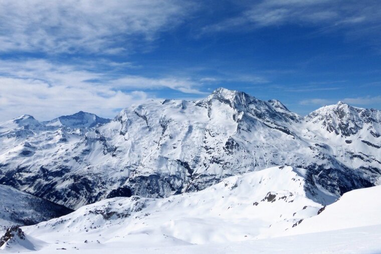 tiny skiers in front of massive mountains