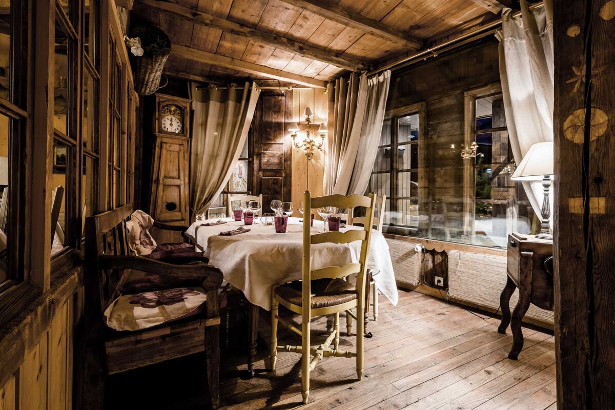 A wooden room with a table and chairs and a clock on the wall