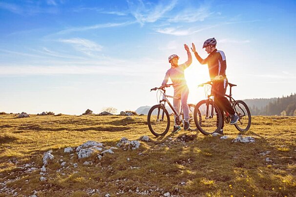 A man and woman giving each other a high five while riding bikes
