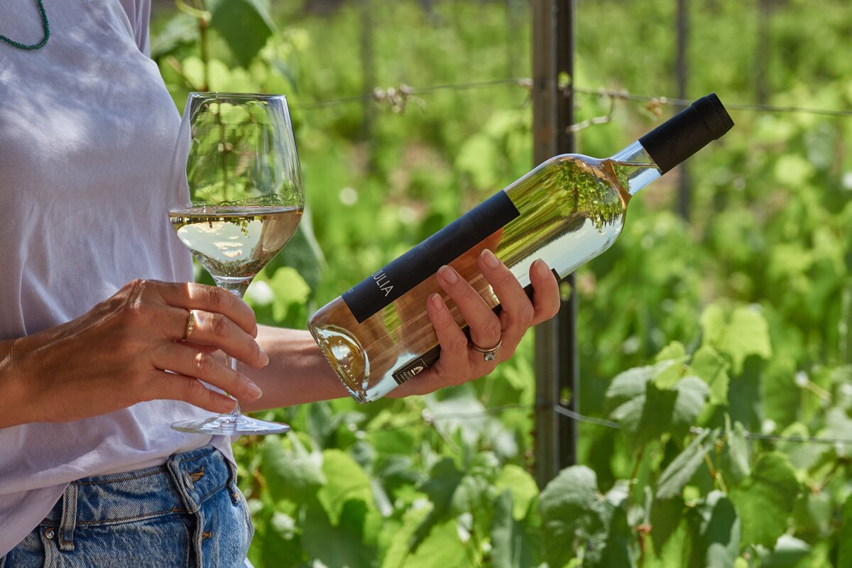 A woman is holding a bottle of villa wine and a glass of wine
