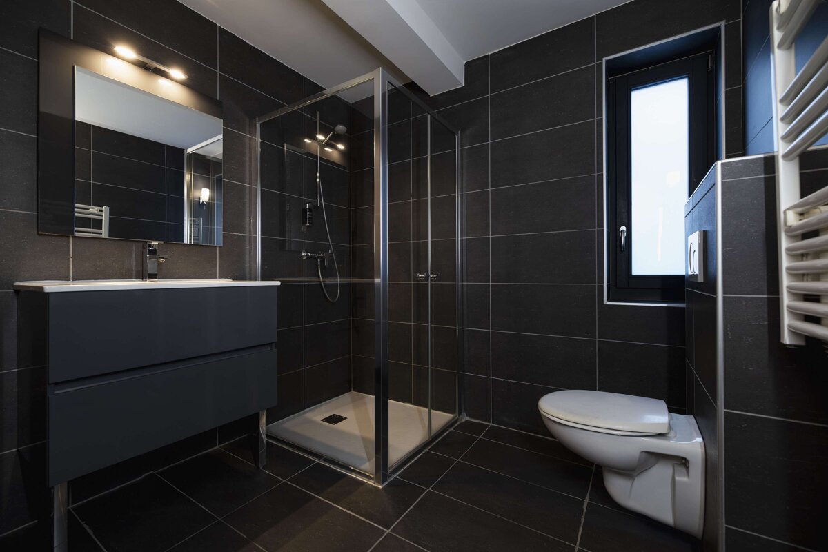 A bathroom with black tiles and a toilet