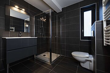 A bathroom with black tiles and a toilet