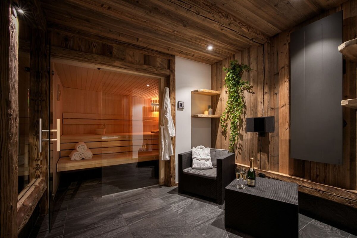 A room with a chair and a glass door leading to a sauna