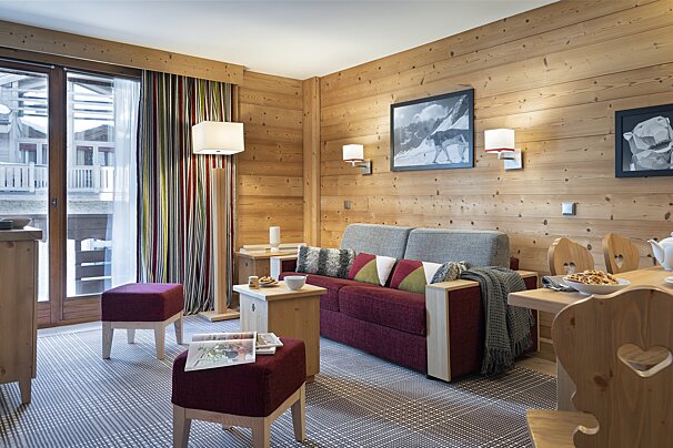 A living room with wood paneling and a red couch