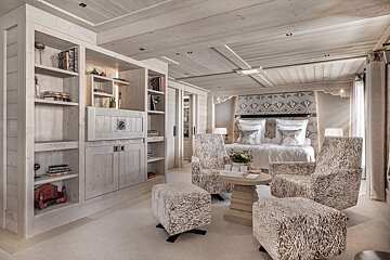 A bedroom with a bed and chairs and a table