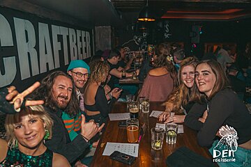 A group of people sitting at a table in front of a sign that says craftbeer