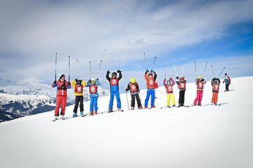 A group of skiers are posing for a picture with their arms in the air
