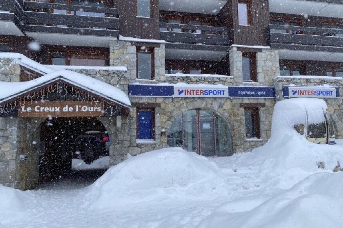 Heavy snowfall blankets a stone and wood building with