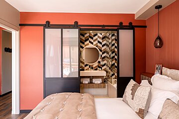 A bedroom with a sliding glass door leading to a bathroom