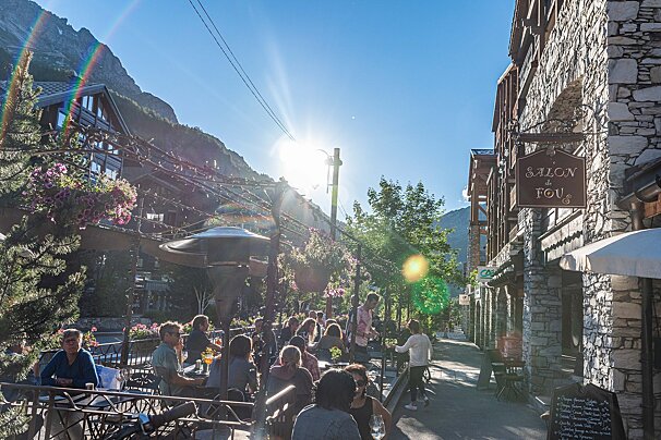 A group of people sit outside a restaurant called salon de fou