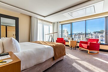 A hotel room with a large bed and two red chairs