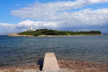 a lighthouse on an island with a small jetty facing it