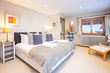 A bedroom with a large bed and a chair