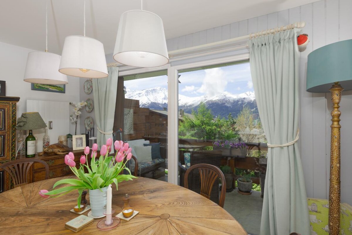 A dining room table with a vase of pink tulips on it