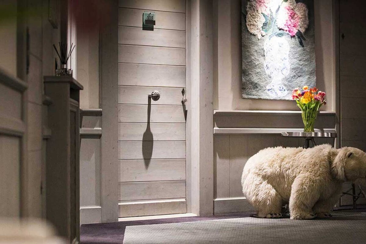 A stuffed polar bear standing in front of a door that says ' a ' on it